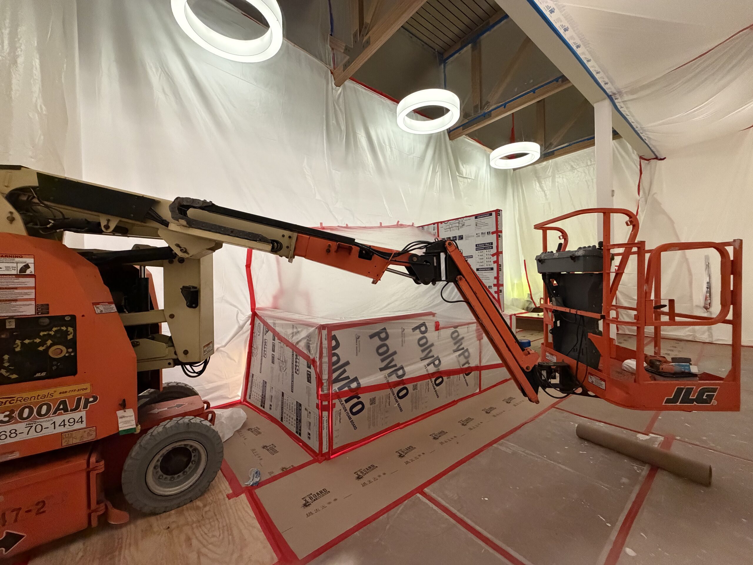 Lifts and equipment staged for a commercial painting project in a warehouse